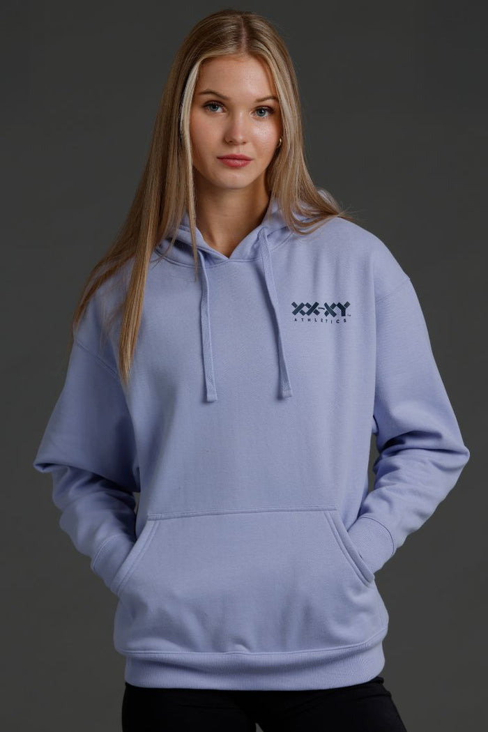 Person wearing a light blue hoodie with a logo on a dark background || Lavender Gray