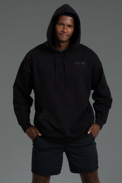 Person wearing a black hoodie with a logo on a gray background || Black