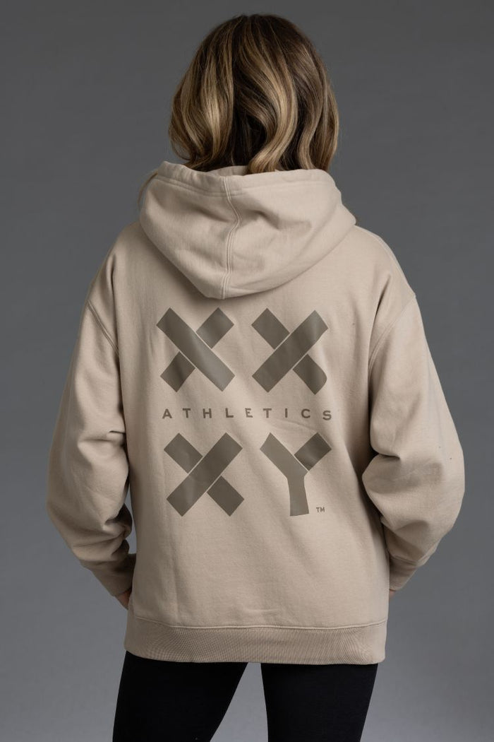 Person wearing a beige hoodie with 'XY Athletics' logo on the back || Taupe