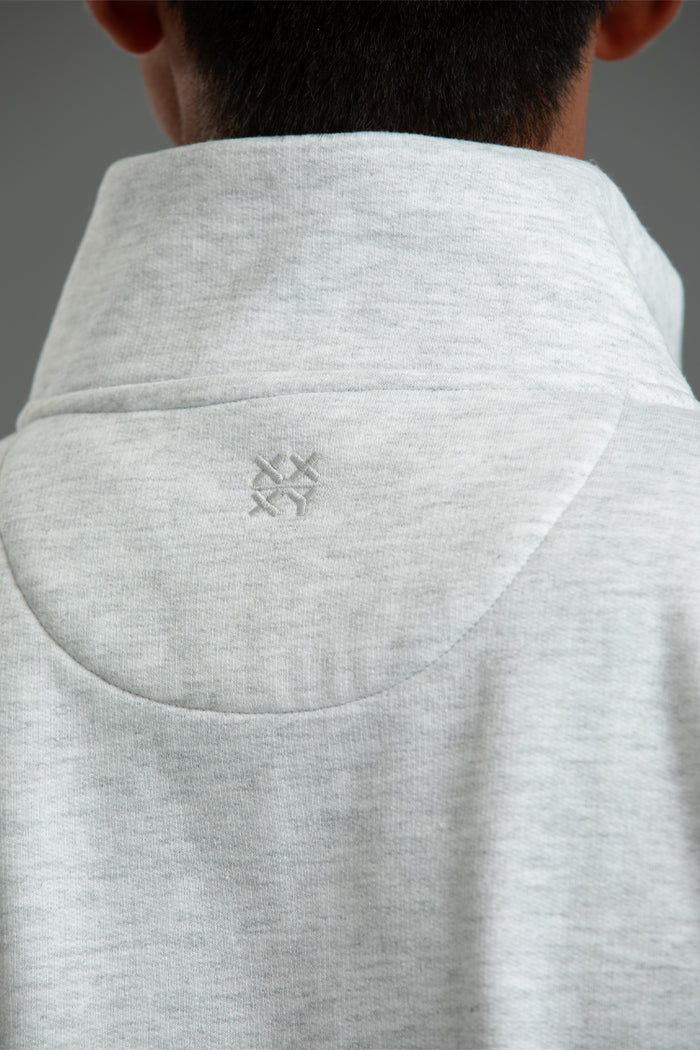 Close-up of a gray hoodie with a brand logo on the collar against a neutral background || Light Heather Gray