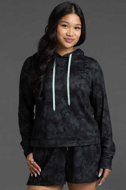Woman wearing a black camouflage hoodie and shorts on a gray background || Black Camo