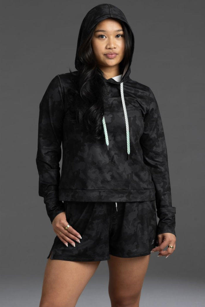 Person wearing a black camouflage hoodie and shorts set on a gray background || Black Camo