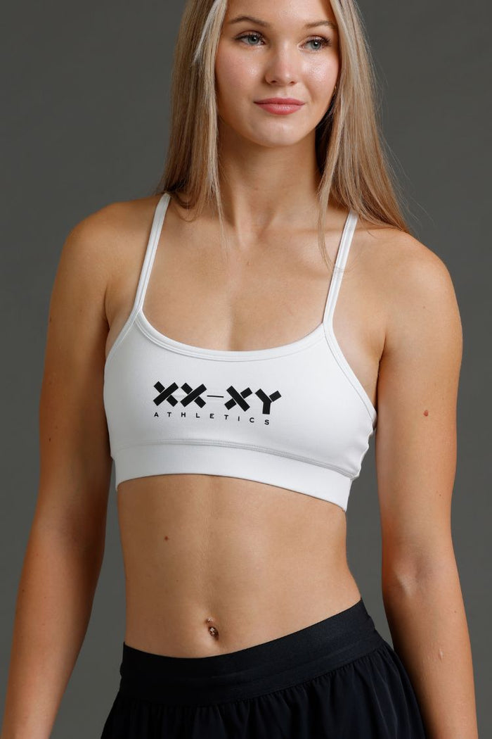 Woman wearing a white sports bra with 'XXXY Athletics' logo || White