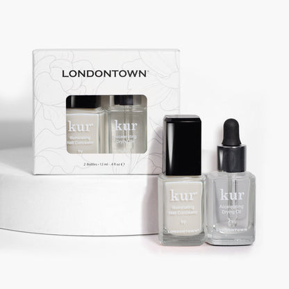 Two bottles of LONDONTOWN Perfect in a Pinch: one Illuminating Nail Concealer and one Accelerating Drying Oil, displayed in front of their packaging on a white surface, offering polished perfection quickly.