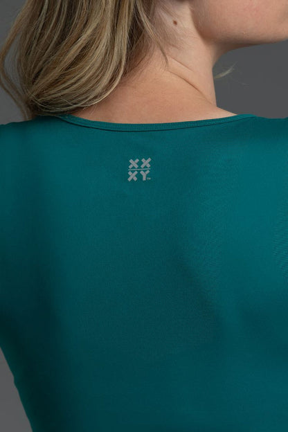 Teal shirt with a logo on the chest against a gray background || Teal